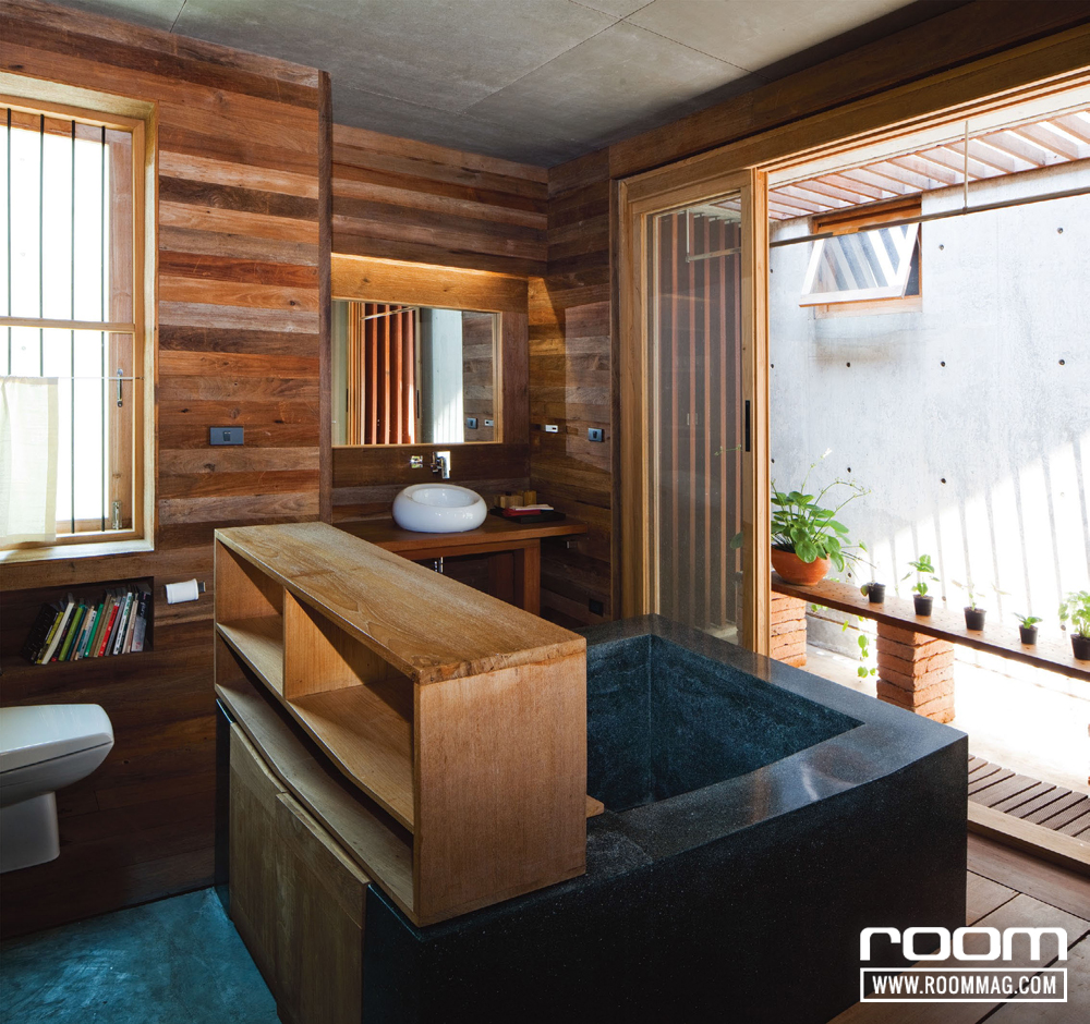 ห้องน้ำในห้องนอนใหญ่วางอ่างอาบน้ำสีดำสำหรับแช่น้ำสไตล์ญี่ปุ่น ทำชั้นวางของตามมุมต่าง ๆ เพื่อรองรับฟังก์ชันการใช้งาน มุมนี้เหมาะนอนแช่น้ำพร้อมชมไม้กระถางฝีมือการจัดวางของครูแหม่มเอง ส่วนด้านบนทำระแนงไม้ นอกจากช่วยกรองแสงแล้ว ยังสร้างลวดลายของเส้นแสงที่แตกต่างตามช่วงเวลา มองแล้วเกิดมิติดูเพลิดเพลินดี