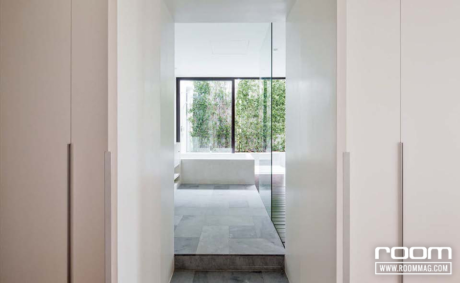 ประตูอาบน้ำในห้องนอนหลักซ่อนอย่างแนบเนียนไปกับหน้าบานประตู มุมมองจากประตูเปิดโล่งทะลุออกไปถึงกรีนวอลล์ซึ่งเป็นผนังของ Outdoor Shower