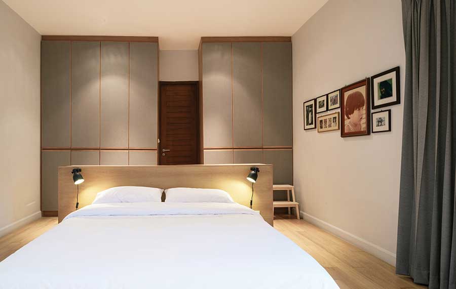 ห้องนอนเรียบง่ายอบอุ่นสบายตา ด้านหลังเป็นบานตู้สูงจรดฝ้าเพดานจึงใช้งานพื้นที่ในทางดิ่งได้อย่างคุ้มค่า